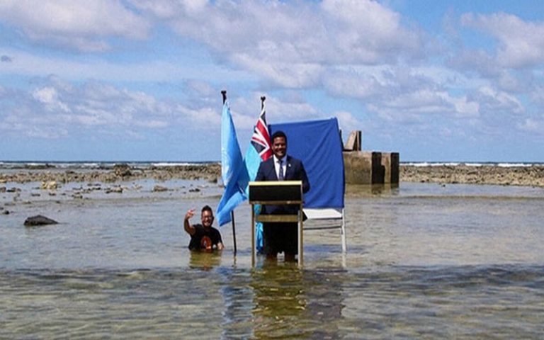 Le ministre des Affaires étrangères de Tuvalu s’exprime derrière un podium de l’eau de mer pour faire voir la menace climatique